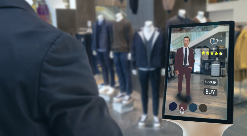 A person using an augmented reality (AR) shopping app on a tablet to virtually try on a suit in a store. The screen displays the price, color options, customer ratings, and a 'BUY' button, integrating the physical and digital shopping experiences.